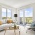 Well-lit living room with mid century modern furniture, lush green plants, and views of the Charles River